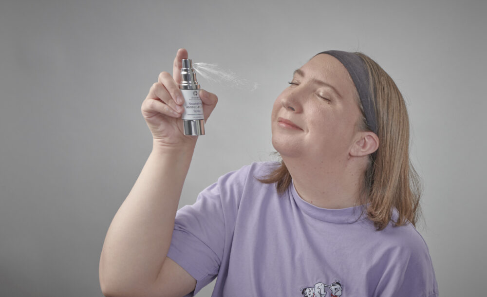woman using amino-plex spray on face